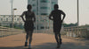 Man and woman jogging together on a bridge at sunset